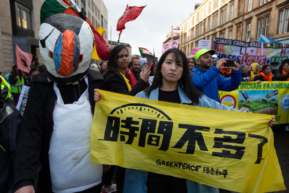 2021年COP26氣候大會期間，綠色和平行動者高舉「時間不多了」標語，與上萬民眾齊聲呼籲會場內的世界領導人：立即為氣候與全人類的未來行動！