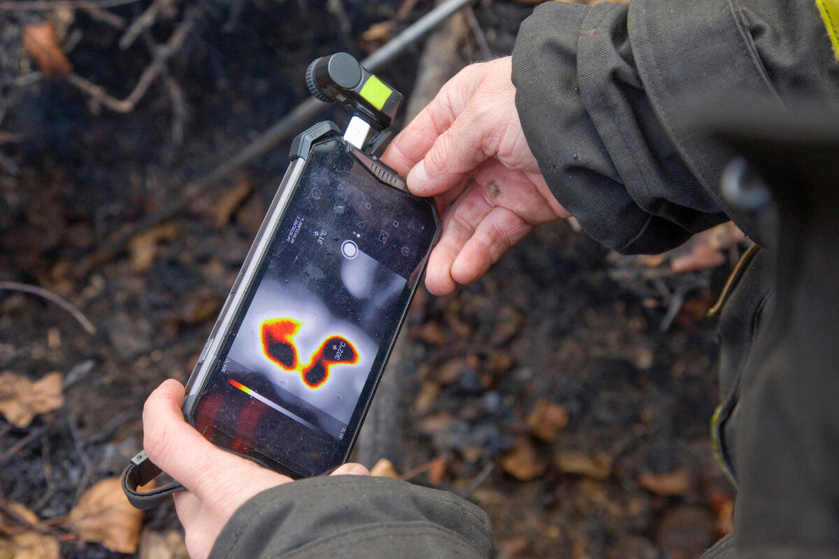 消防人員以手機和熱像儀拍攝泥炭地的熱圖像。