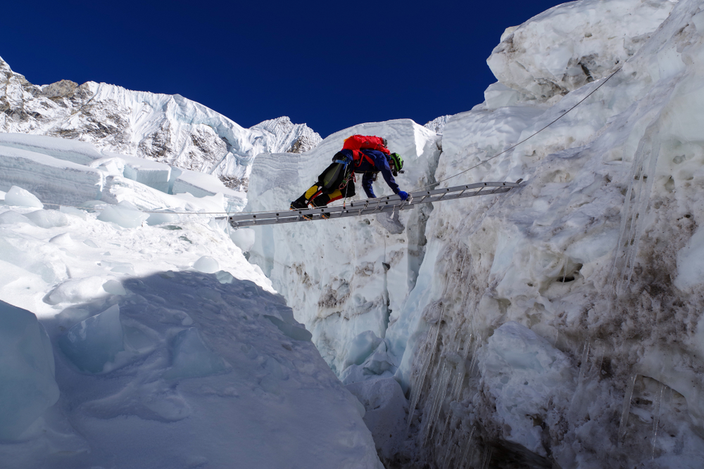 攀登聖母峰須穿過許多冰川，登山者橫架長梯小心前進。