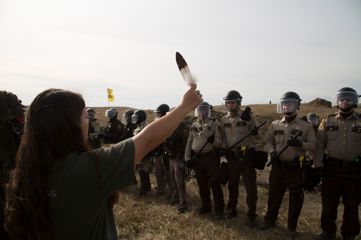 即使面對美國國家警衛軍及警隊鎮壓,立岩蘇族人依然毫無懼色,手持老鷹羽毛以和平行動守護部落家園。