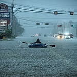 A person in an inflatable boat paddles down flooded Highway 610 in the Houston area as rains associated with Hurricane Harvey continue to fall in the area.