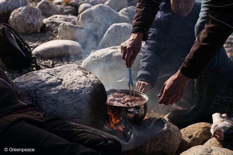 Former mayor of Clyde River, Jerry Natanine and his wife Christine cook up a pot of seal meat, during a picnic of country foods, near Clyde River. Greenpeace has come to deliver solar panels and offer a series of lectures and workshops in Clyde River.