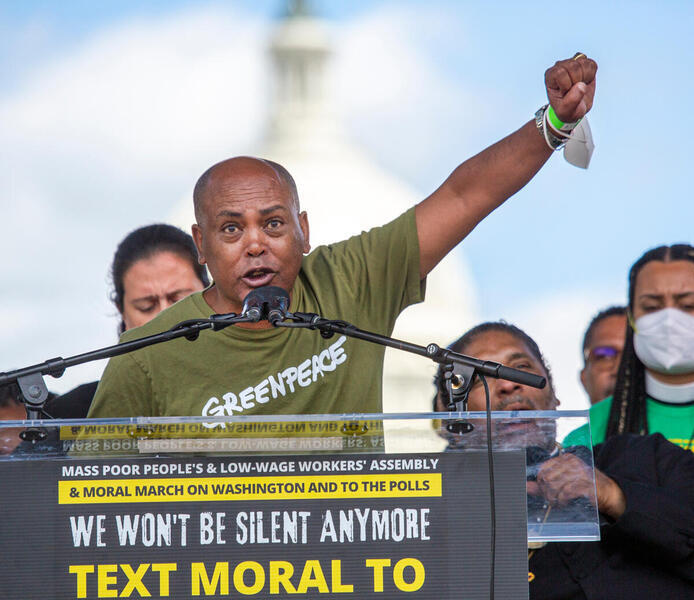 Activist speaking into a microphone with a raised fist.