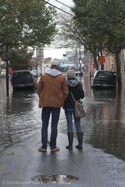 A couple stands on a patch of dry land and surveys the flooded streets of Hoboken in the aftermath of Hurricane Sandy.
