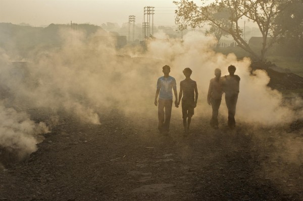 Local people in Aina village and toxic fumes rising from the ground caused by burning coal at the nearby Jharia coal mine. 