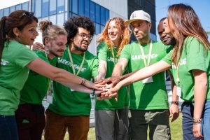 7 campaigners in Greenpeace shirts put their hands in for a team chant