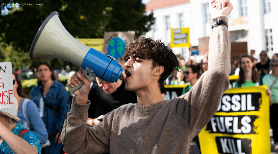 Activist rallies the crowd using a megaphone at a protest against fossil fuels.